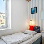 Ein Schlafzimmer mit Bett, Nachttisch und Fenster mit Blick auf Häuser.