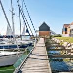 Holzsteg führt zu Booten im Hafen mit Häusern am Ufer.