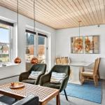 Wohn- und Essbereich mit Holzdecke, zwei grünen Sesseln und Essgruppe.