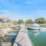 Holzsteg führt zu einem Anleger mit Booten. Hintergrund: Häuser und Marina Park.