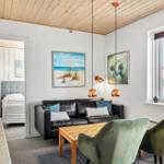 Wohnzimmer mit Sofa, zwei Sesseln und Blick auf Hafen. Schlafzimmer im Hintergrund.