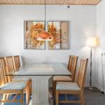 Essbereich mit Glasplatte, Holzstühlen und Wandbildern.