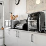 Küchenzeile mit Mikrowelle, Toaster und Kaffeemaschine neben Fenster.