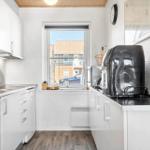 Küche mit Fenster, Spüle, Geschirrspüler und Küchengeräten.