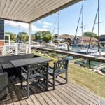 Terrasse mit Sitzgruppe überblickt einen Bootssteg mit Segelbooten.