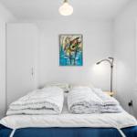 Schlafzimmer mit Bett, Kleiderschrank und Wandbild.