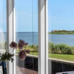 Blick aus dem Fenster aufs Wasser und eine grüne Insel mit einem Haus.