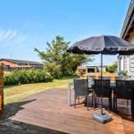 Terrasse mit Tisch, Stühlen und Sonnenschutz. Grill und Garten sind sichtbar.