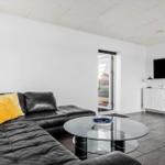 Schwarzes Ledersofa mit gelben Kissen, Glas-Tisch und Fernseher an der Wand.