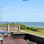 Terrasse mit Liegestühlen und Blick aufs Wasser und Windräder.