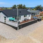 Moderne Villa mit Terrasse, Sonnenliegen und Blick aufs Wasser.