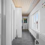 Flur mit Holzdecke, Fenstern und Wandbild.