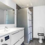 Badezimmer mit Waschmaschine, Dusche und Toilette.