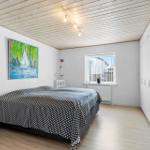 Schlafzimmer mit Bett, Wandbild und Fenster. Holzdecke und Kleiderschrank sichtbar.