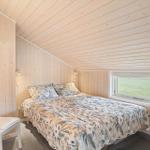 Schlafzimmer mit Bett, Fenster und Stuhl an Holzwand.