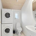 Badezimmer mit Waschmaschine, Trockner, Toilette und Waschbecken.