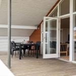 Terrasse mit Tisch und Stühlen, Zugang zum Innenraum durch Glastüren.