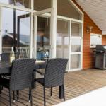 Terrasse mit Tisch, Stühlen und Grill. Durchgehende Glasfront zum Innenraum.