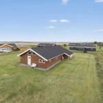 Holzhaus mit Garten, mehrere Häuser im Hintergrund, klare Himmel