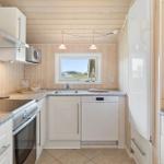 Küche mit weißen Schränken, Spüle, Herd und Kühlschrank.