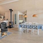 Wohn- und Essbereich mit Holzwand, Kamin und Esstisch.