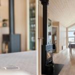 Küche mit Holzvertäfelung und Esstisch mit Tischdecke. Kaminofen mit brennendem Feuer.