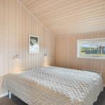 Schlafzimmer mit Holzwand, Bett und Fenster. Wandlampe und Bild an der Wand.