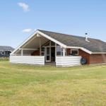 Ein Haus mit braunem Holz und weißer Veranda auf grünem Grund.