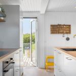 Küche mit Holzoberflächen, goldfarbenem Wasserhahn und Blick auf die Terrasse.