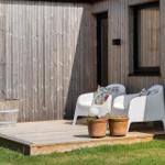 Terrasse mit zwei weißen Sesseln, Pflanzen und Holzwand.