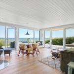 Großes Wohnzimmer mit Blick aufs Meer, Holzboden und Kamin.