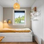 Ein Schlafzimmer mit Bett, Fenster und Wandregal.