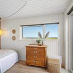 Schlafzimmer mit Blick aufs Meer und Holzkommode.