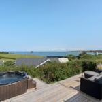 Terrasse mit Whirlpool und Sitzgruppe. Blick auf Meer und Landschaft.
