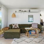 Wohnzimmer mit grünem Sofa, runder Couchtisch und Blick auf Balkon.