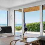 Wohnzimmer mit Meerblick, Fernseher und Terrasse mit Liegestuhl.