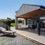 Moderne Holzhütte mit Terrasse, Sonnenliege und Sitzgelegenheit unter Dach.