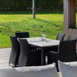 Terrasse mit Tisch und sechs Stühlen, Blick auf grünen Rasen