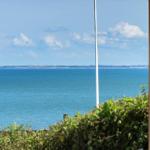 Blick durch Fenster auf tiefblaues Meer und Himmel mit Wolken.