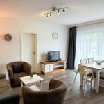 Wohn- und Essbereich mit Sofa, Stühlen, TV und Tisch.