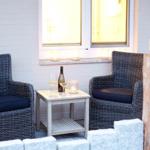 Zwei Sessel mit Kissen, Tisch mit Wein und Kerzen vor Fenster.