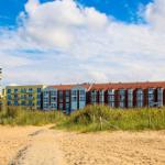 Strand mit Dünen, Ferienhäuser und einem Strandkorb.