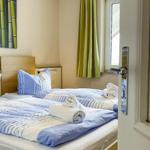 Zweibettzimmer mit blau-weißen Bettwäsche und grünen Vorhängen.
