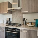 Küche mit Dunstabzugshaube, Herd und Backofen sowie Küchenutensilien.