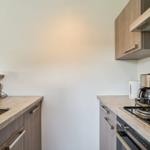 Küche mit Spüle, Kochfeld, Kaffeemaschine und Schränken.