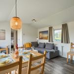 Essbereich mit Tisch und Stühlen, Sofa und Fenster mit Blick nach draußen.