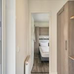 Schlafzimmer mit Bett und Kleiderschrank. Durchgang zur Terrasse mit Blick auf Garten.