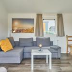 Wohnzimmer mit grauem Sofa, Holzboden und Fenster mit Blick.