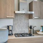 Küche mit Gasherd, Dunstabzug und Holzschränken.