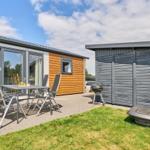 Terrasse mit Sitzgruppe, Grill und Gartenhaus neben modernem Ferienhaus.